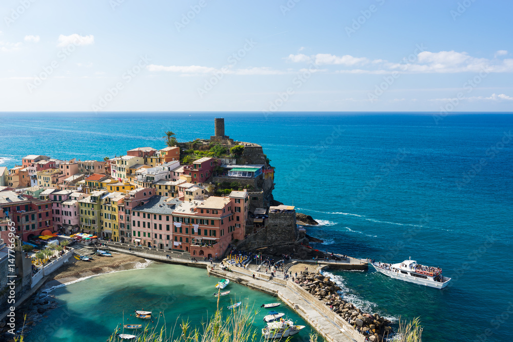 Color full Cinque Terre Vernazza tourist harbor view in sunny summer day with boat full of tourists in Italy