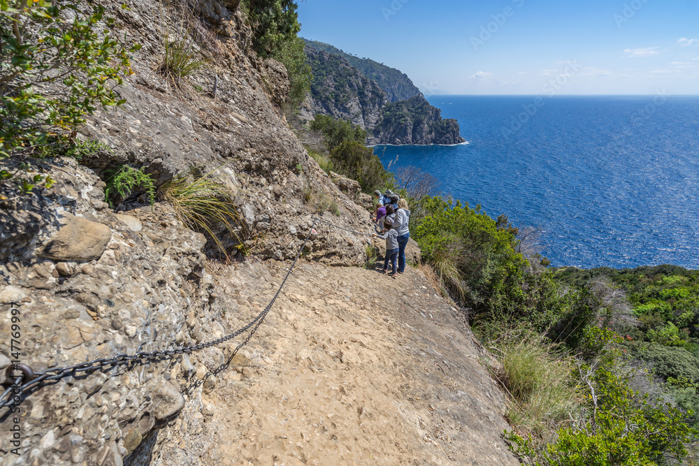 Undefined people walking on the rocks on Tigullio hiking trail, Liguria, Italy