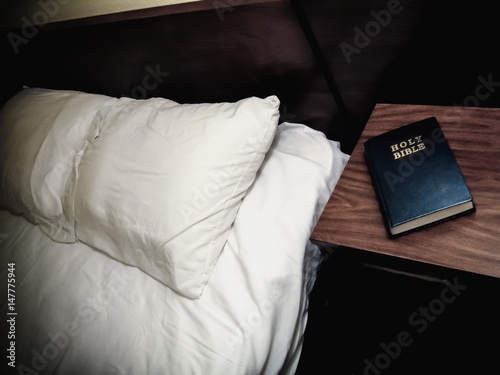 Holy Bible Nightstand Motel Room. Motel room bed with a bible on a the night stand. photo