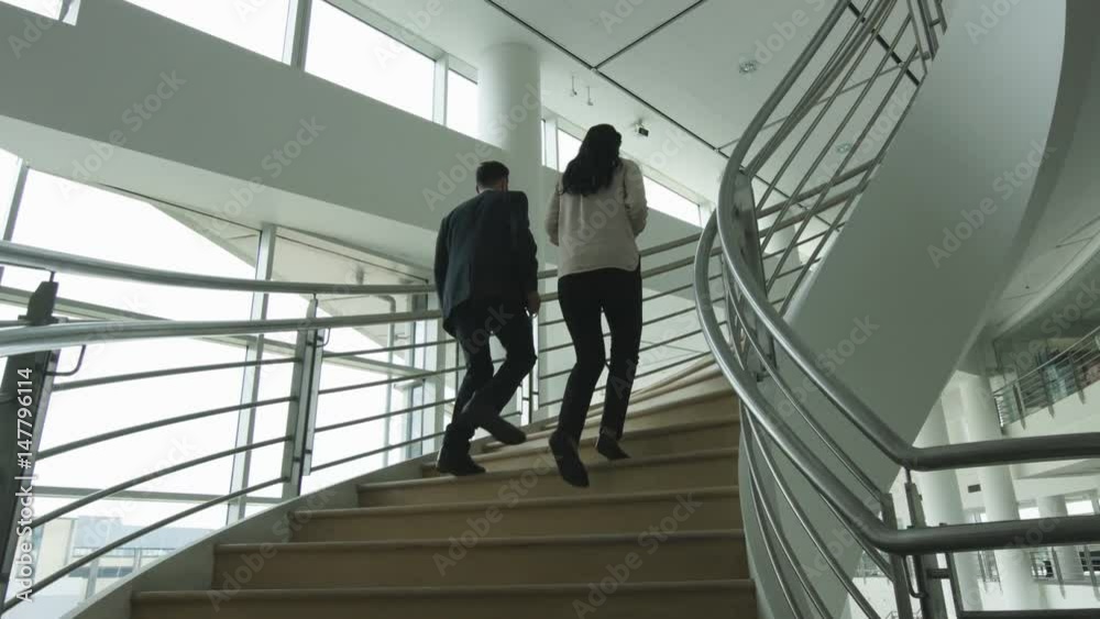 Businessman walking up spiral staircase in office