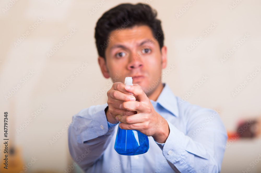 Handsome young caucasian male pointing cleaning spray bottle in front of him Handsome young caucasian male pointing cleaning spray bottle in front of him