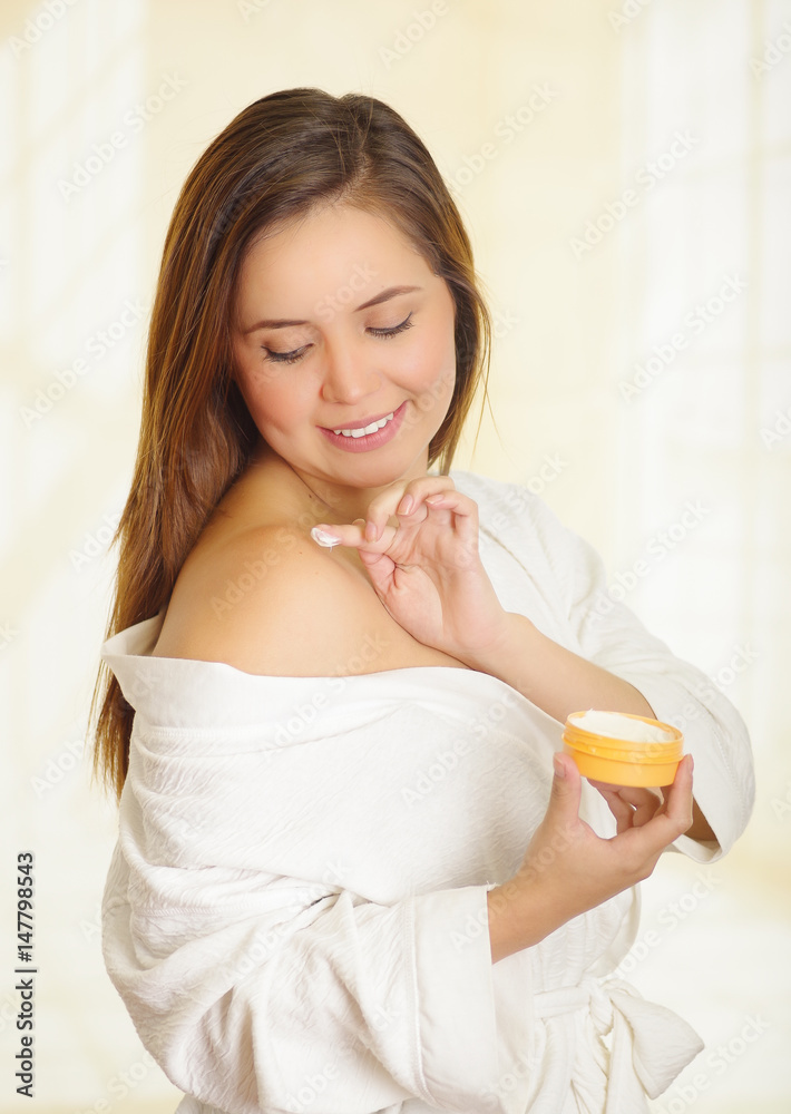 Beautiful smiling young woman adding a cream body over her shoulder Beautiful smiling young woman adding a cream body over her shoulder