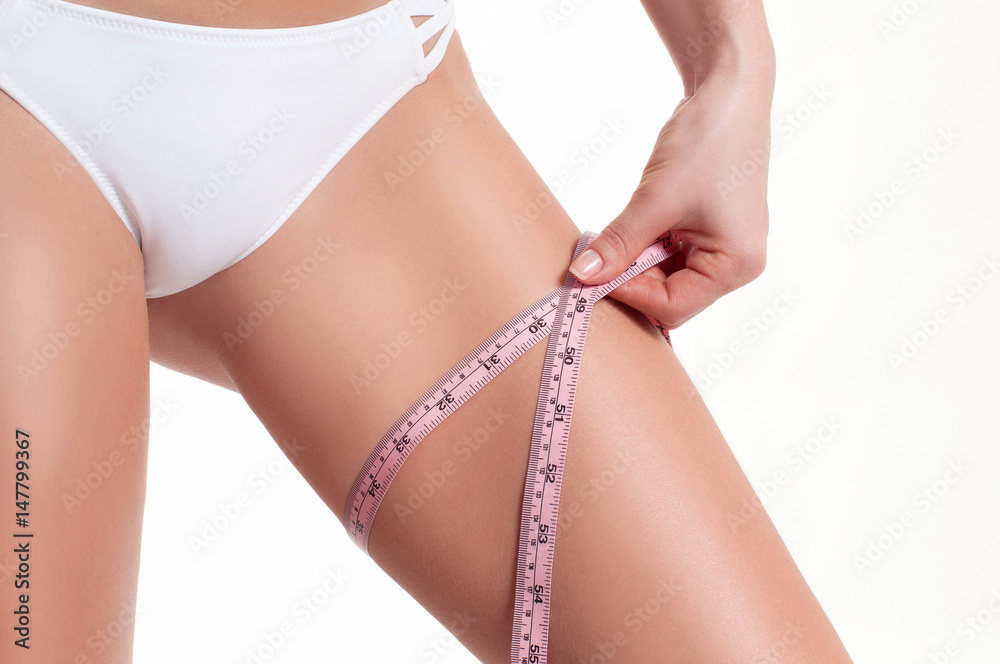 Diet concept, woman measuring her leg with a measure tape Diet concept, woman measuring her leg with a measure tape