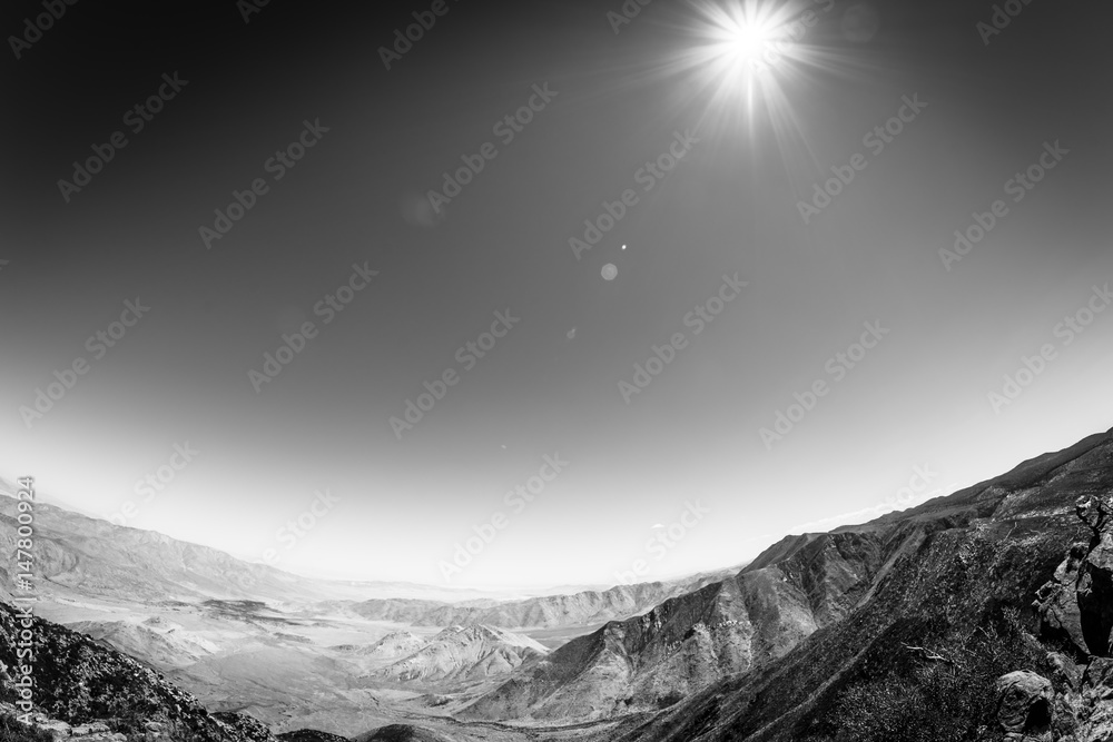 Black and white sun over desert mountains