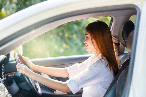 Young asian woman driver driving a car on the road in countryside.