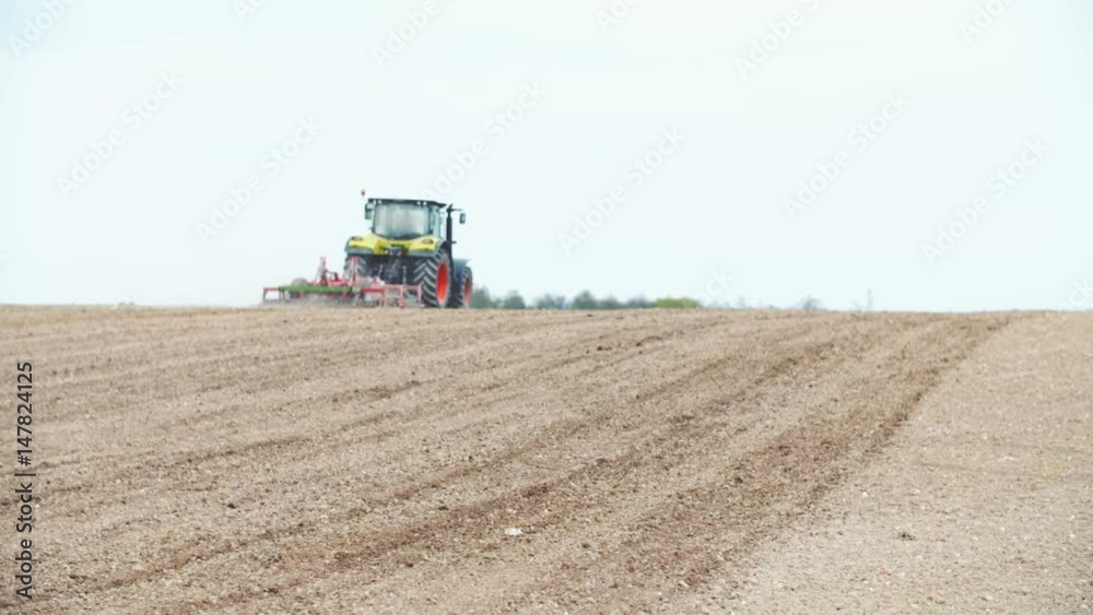 Tractor plowing field using harrows (wide shoot) Tractor plowing field using harrows (wide shoot)