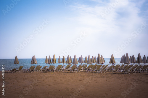 Sun beds and umprellas on an empty tropical sandy beach, Rethimno, Crete, Greece