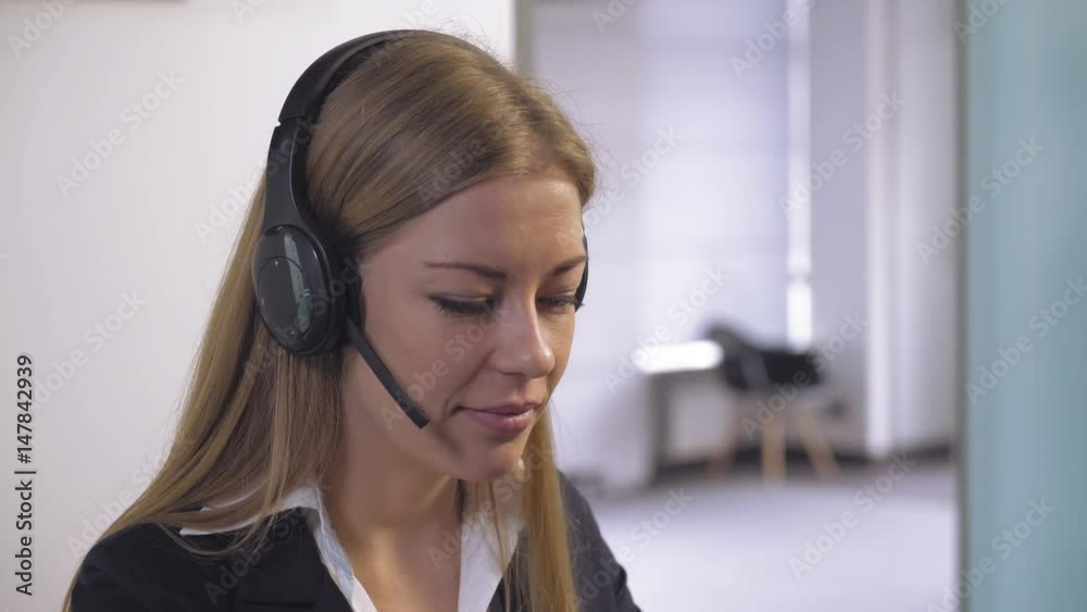 portrait caucasian woman at working place. Young friendly secretary talking with client using headphone. Smiling worker in support service consulting customer or give advice. portrait caucasian woman at working place. Young friendly secretary talking with client using headphone. Smiling worker in support service consulting customer or give advice.