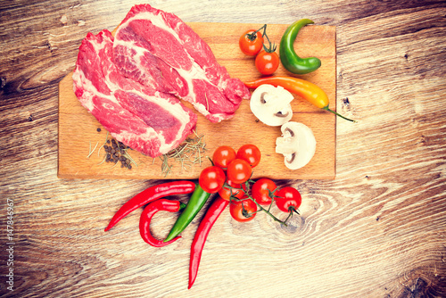 Fresh steaks with vegetables on the wooden table. Toned image