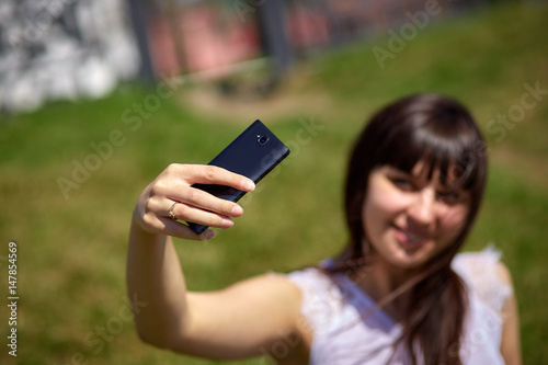 Beautiful oriental-looking girl doing selfie on a smartphone © vadiar