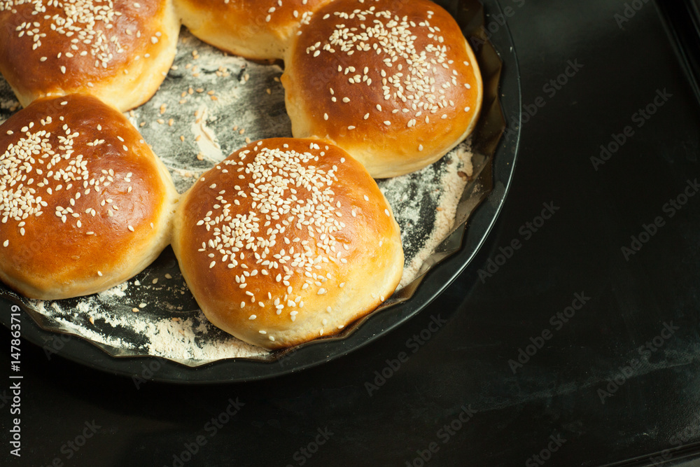 buns for burgers with sesame in a baking form on black background, copy space 2
