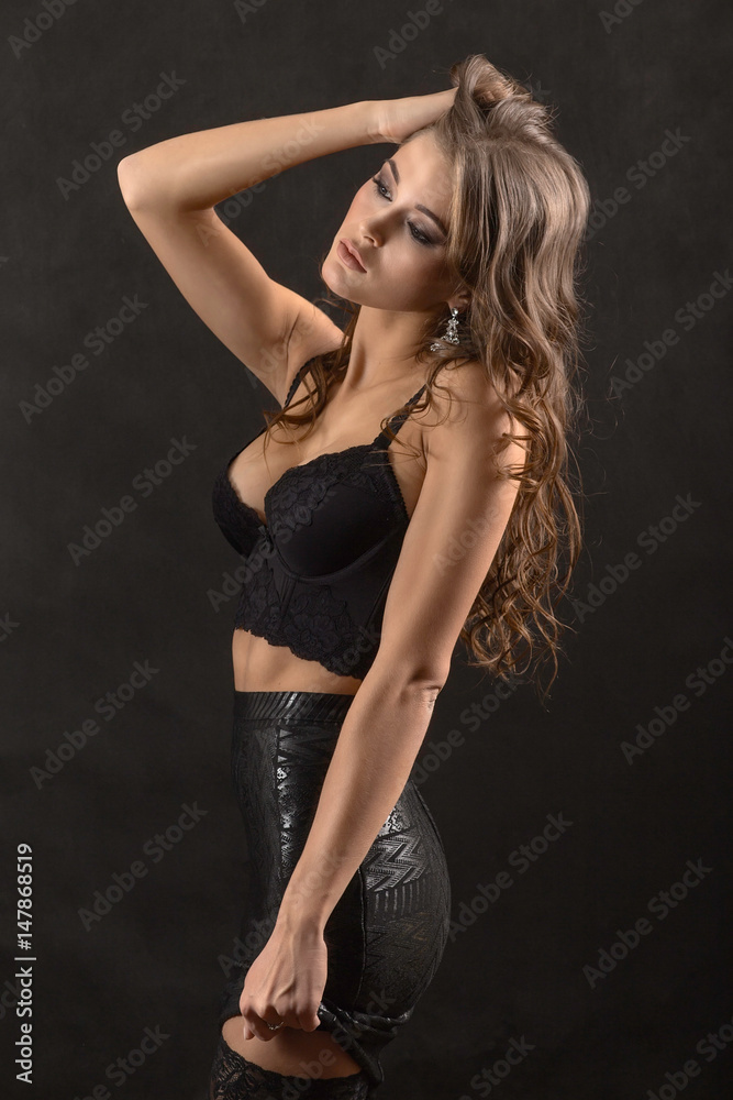 Side view of seductive female posing in sexy lingerie on black background. Side view of seductive female posing in sexy lingerie on black background.