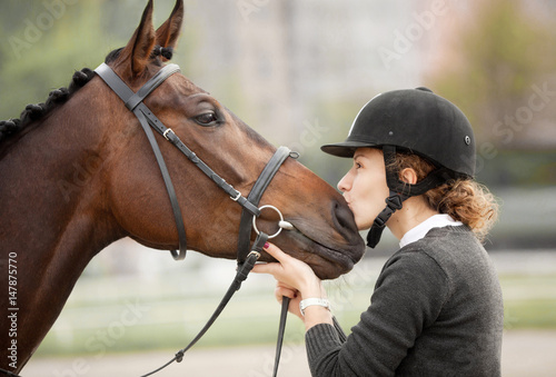 Atrakcyjna młoda kobieta całuje swojego konia