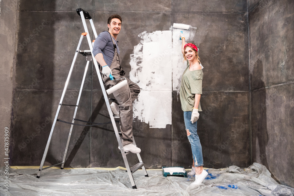 young couple painting wall together, renovation home concept