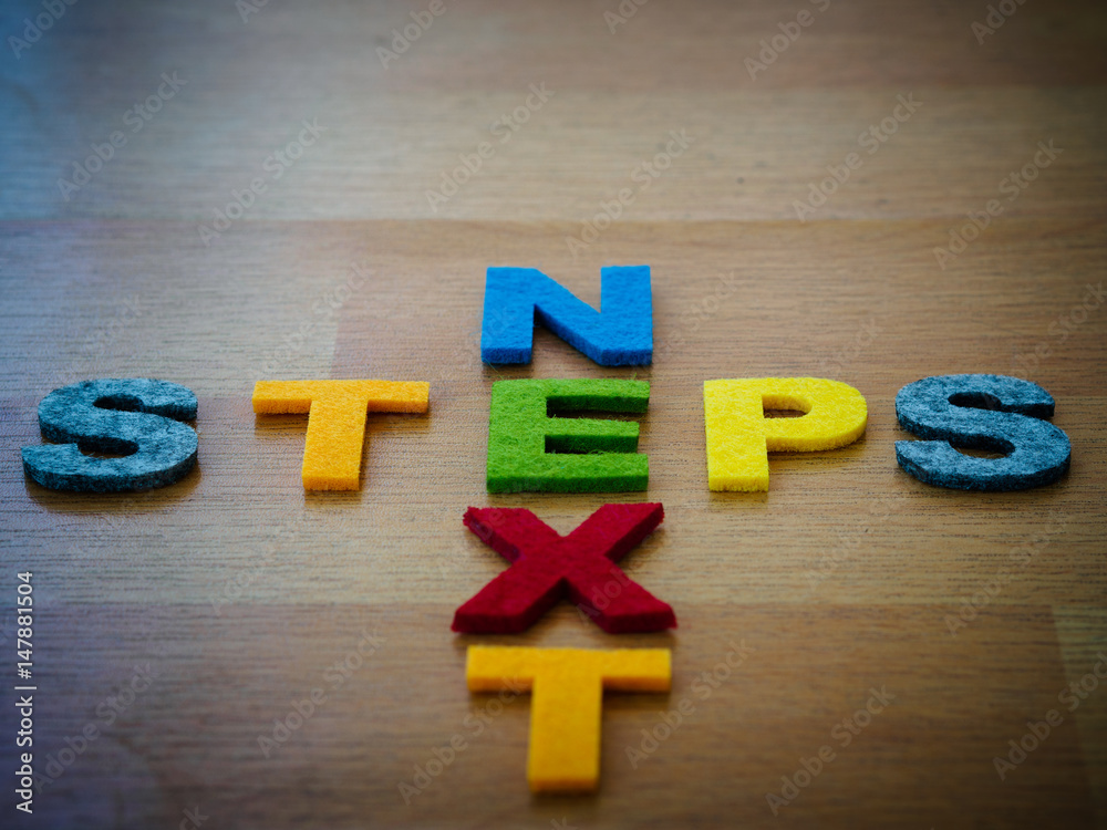 Obraz premium next steps concept in colorful letters on wooden blackboard