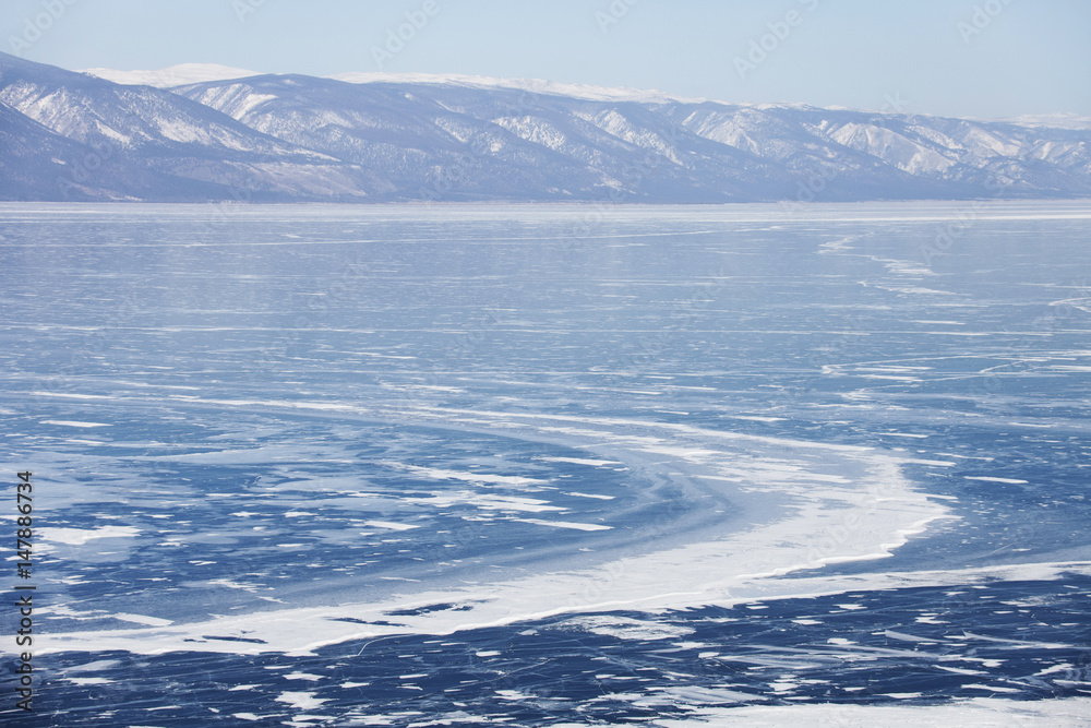 Winter landscape. Lake Baikal ice. Mountain shore.