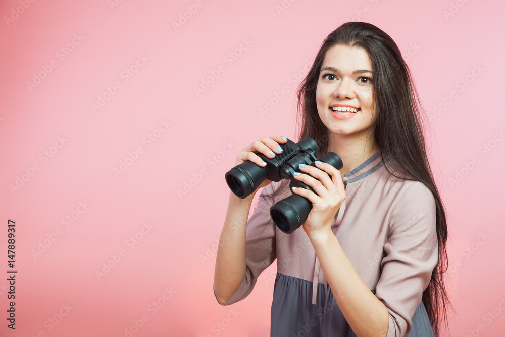 Young woman with binocular glasses on pink background Young woman with binocular glasses on pink background