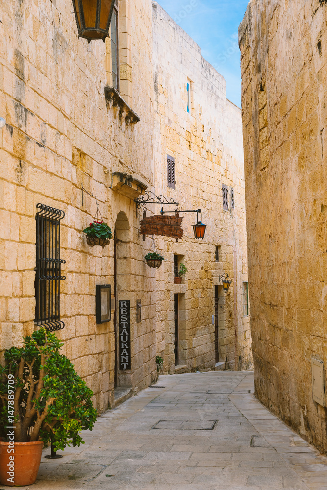 Narrow street of Silent City with a small restaurant, Mdina, Malta