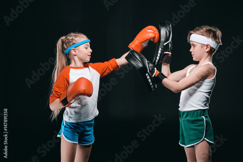 side view of kids pretending boxing isolated on black, active kids concept © LIGHTFIELD STUDIOS