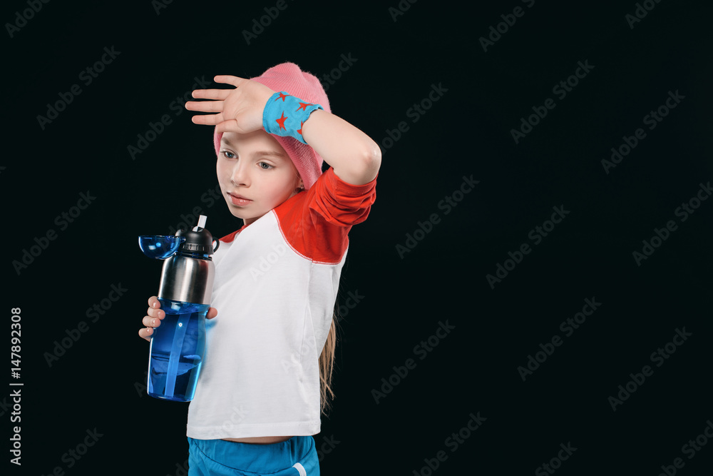 tired girl in sportswear holding sport bottle isolated on black. athletics children concept