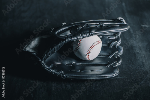 Photography Close-up view of leather baseball glove and ball on black