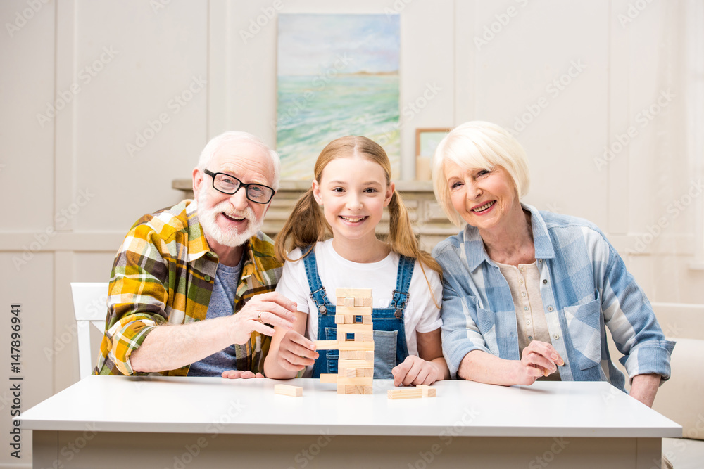 Happy family playing jenga game together and smiling at camera