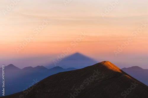 Crater rim of mount Agung in Bali at sunrise summit. Above the clouds, colorful landscape. First rays of rising sun in orange color. Top of Agung Volcano