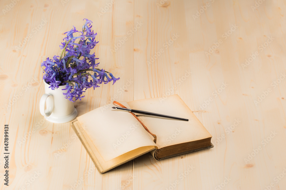 Fototapeta premium lily flowers with open aged notebook and brush on wooden table