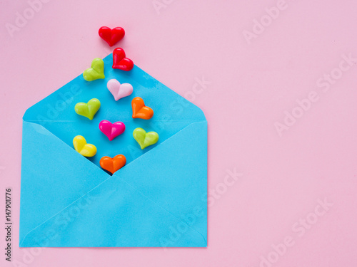 Love letter valentine's day concept. Closeup image of blue letter with copy space arranged on pink background  and colorful of hearts © Siam