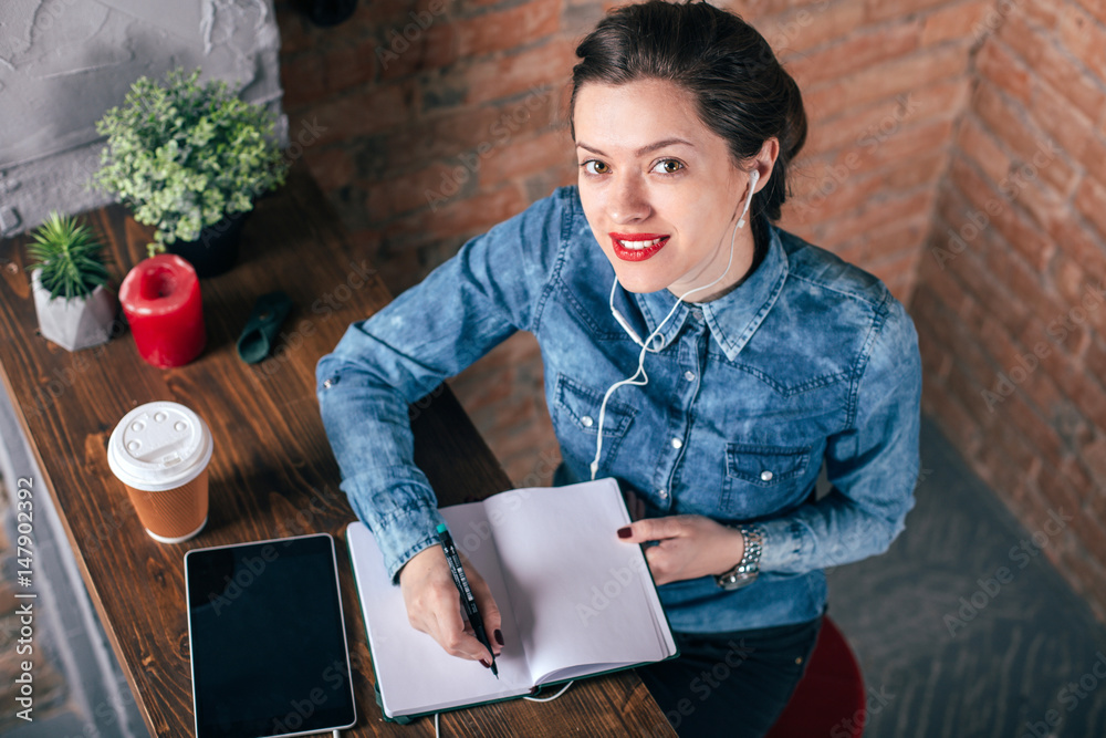 Obraz premium Beautiful young female freelancer with notepad and tablet have a coffee break in loft interior room