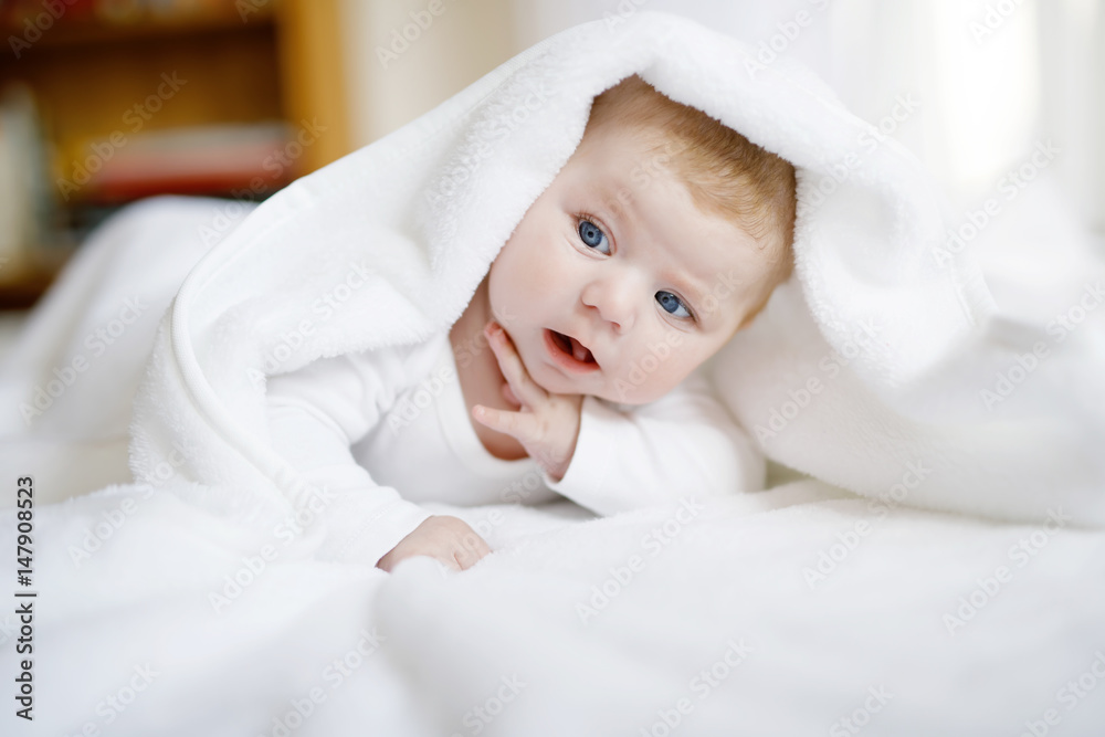 Baby girl wearing white towel or winter overal in white sunny bedroom Baby girl wearing white towel or winter overal in white sunny bedroom