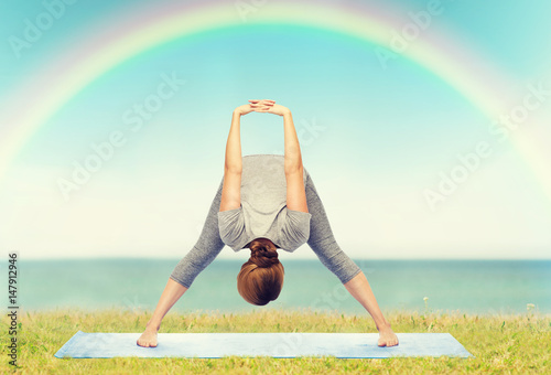 woman making yoga wide-legged forward bend on mat