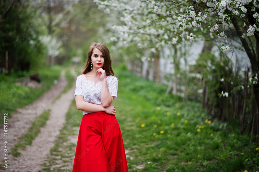 Portrait of beautiful girl with red lips at spring blossom garden, wear on red dress and white blouse. Portrait of beautiful girl with red lips at spring blossom garden, wear on red dress and white blouse.