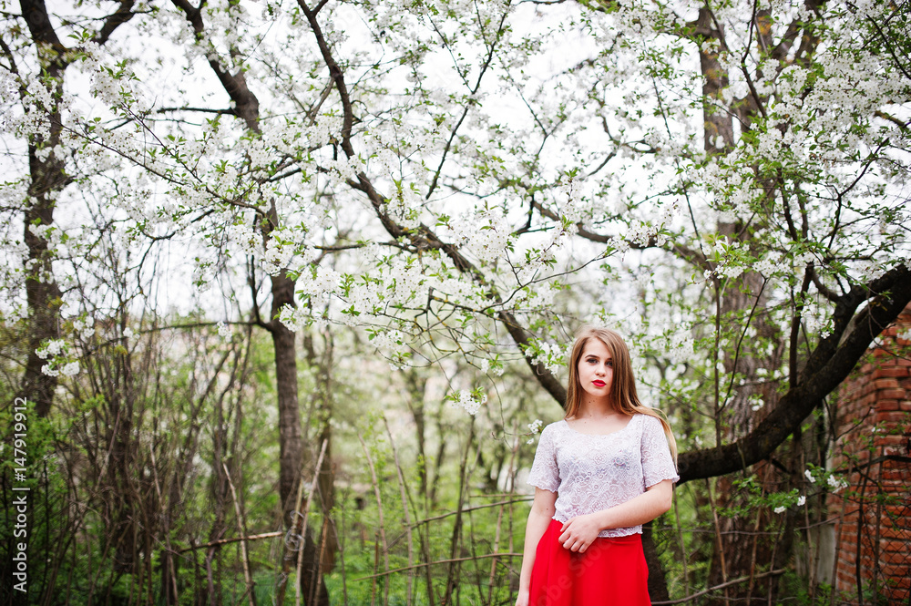 Portrait of beautiful girl with red lips at spring blossom garden, wear on red dress and white blouse. Portrait of beautiful girl with red lips at spring blossom garden, wear on red dress and white blouse.
