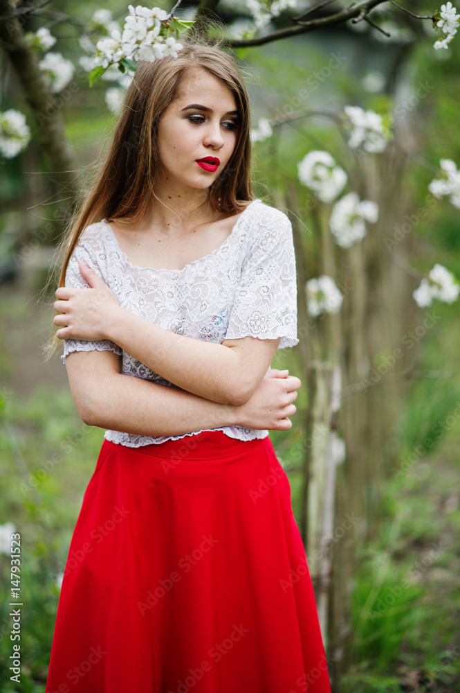 Portrait of beautiful girl with red lips at spring blossom garden, wear on red dress and white blouse. Portrait of beautiful girl with red lips at spring blossom garden, wear on red dress and white blouse.