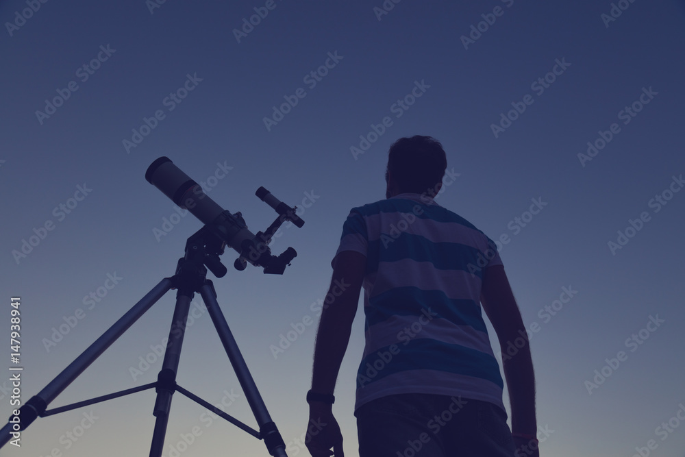 Man looking at the night sky through a telescope.