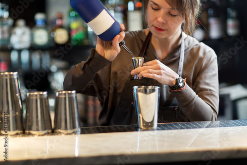 barmaid with shaker preparing cocktail at bar