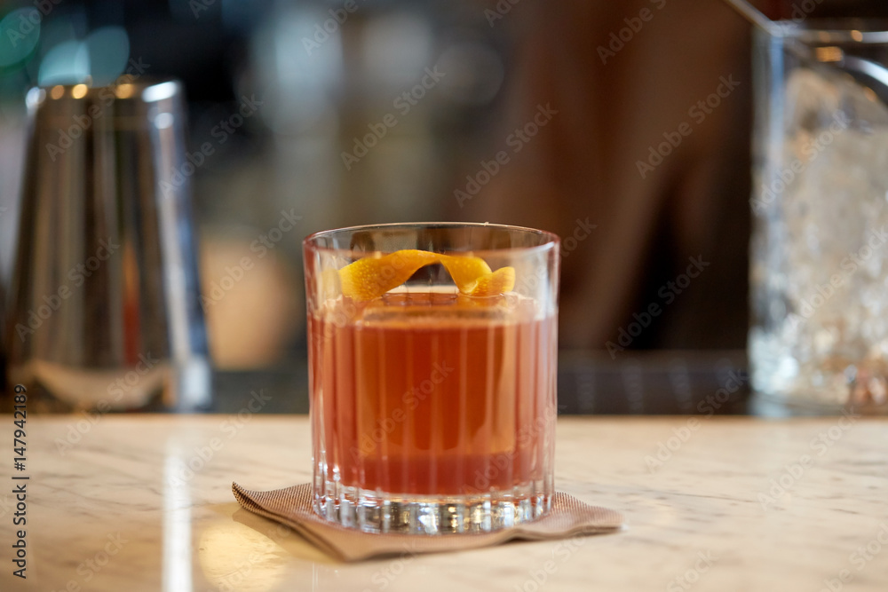 glass of cocktail with orange peel at bar glass of cocktail with orange peel at bar