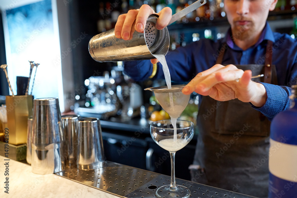 bartender with shaker preparing cocktail at bar