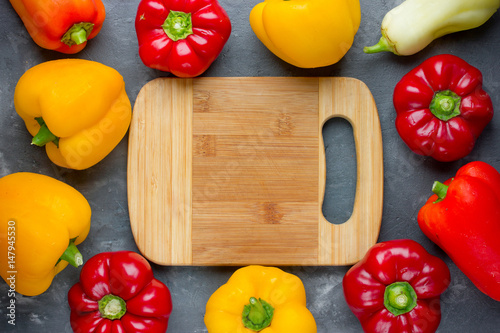 Colorful peppers on table with empty cutting board photo