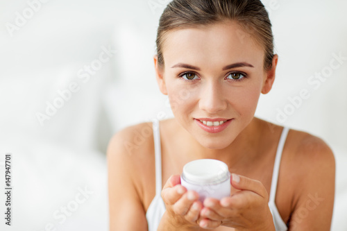 close up of happy woman holding cream jar