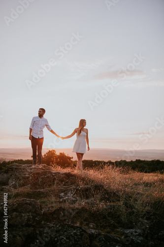 couple holding hands with sunset