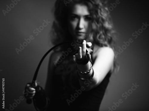 Beautiful sexy domineering woman holding a whip in her hands She is dressed in a corset and and gloves. BDSM. In sharpness, the hand and the tip of the whip.