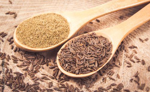 Ground cumin in a spoon and whole cumin photo