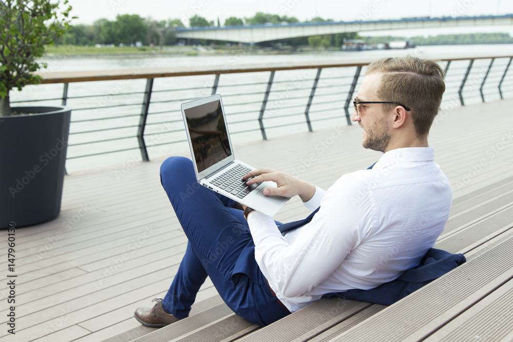 Handsome young businessman working on laptop sitting on the stairs outdoor Handsome young businessman working on laptop sitting on the stairs outdoor