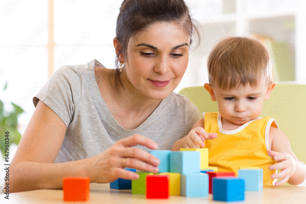 Young mummy and her kid play with cubes toys in nursery Young mummy and her kid play with cubes toys in nursery
