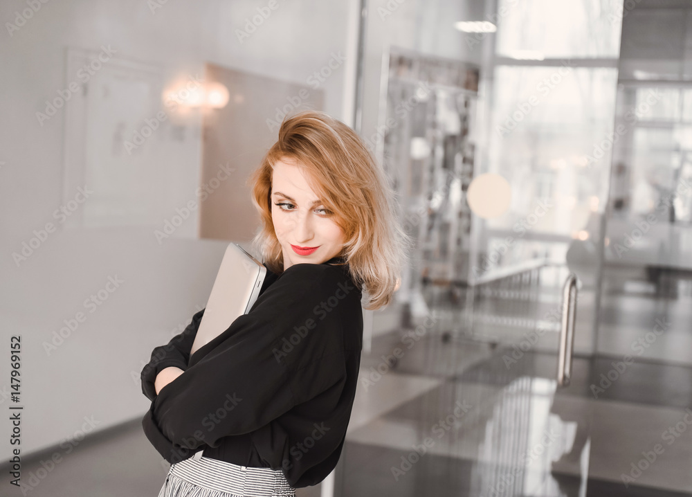 Girl young beautiful blonde hipster with red lips inside in black blouse holds smart laptop tablet using on keyboard Girl young beautiful blonde hipster with red lips inside in black blouse holds smart laptop tablet using on keyboard
