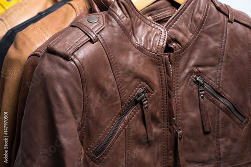 Different color leather jacket hanging on rack on white background