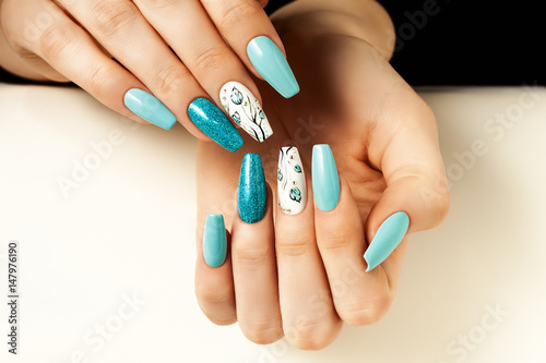 Blue female nails elongated with a design.