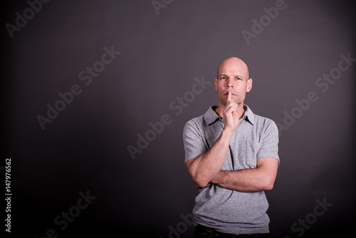 Mann mit grauem Poloshirt legt den Zeigefinger auf den Mund, nachdenklicher Blick © Petra Homeier